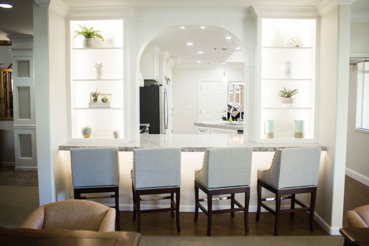 A modern kitchen interior with bar stools and decorative shelves.