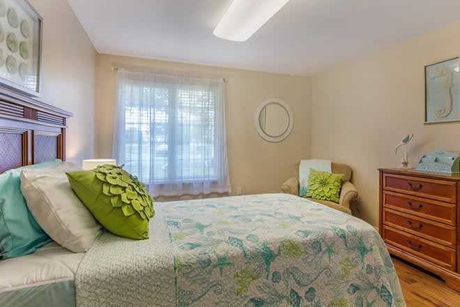A cozy bedroom with a bed, decorative pillows, and a window.