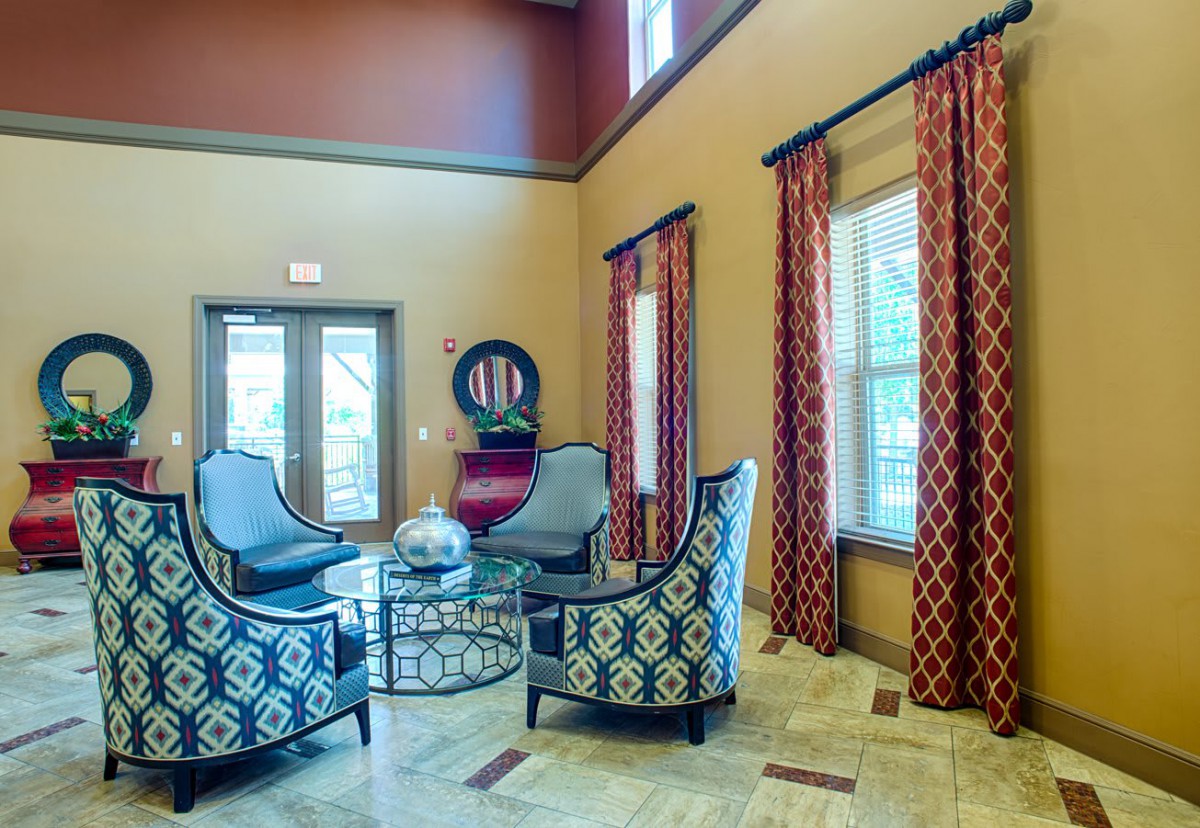 A cozy living room area featuring patterned chairs and curtains, with large windows providing natural light.