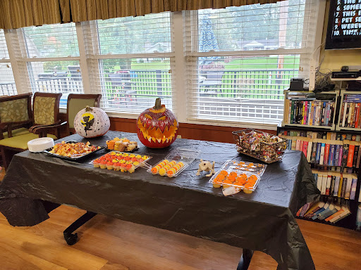 A festive Halloween table decorated with themed treats and a carved pumpkin centerpiece.