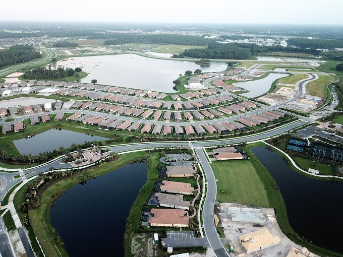 Aerial view of a suburban residential area with houses and surrounding water bodies.