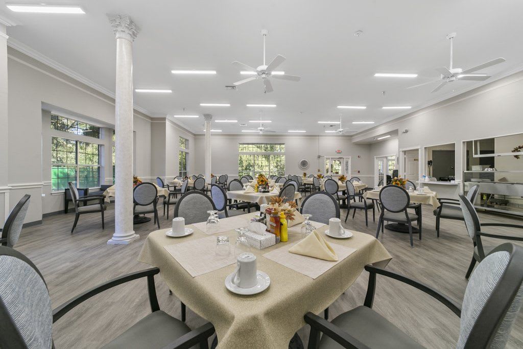 A spacious and well-lit dining area with neatly arranged tables and chairs, decorated with flowers.