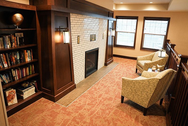 A cozy living room with a fireplace, armchairs, and large windows.