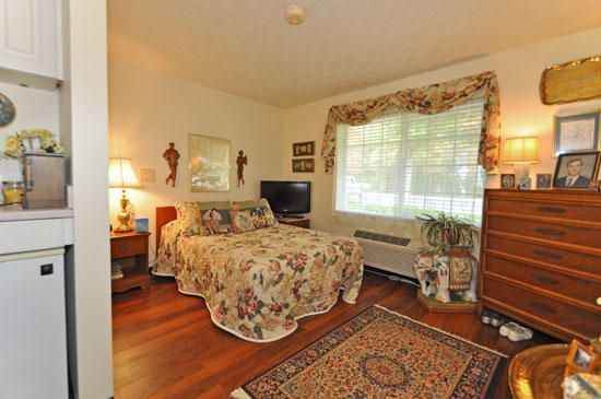 A cozy, traditionally styled bedroom featuring floral bedding and a large window with decorative curtains.