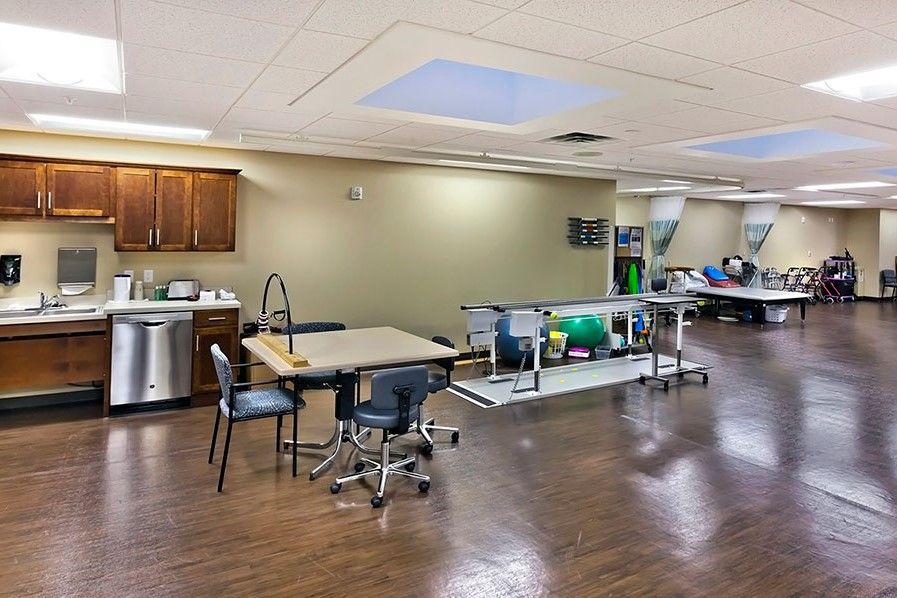 A spacious physical therapy room equipped with exercise machines and a seating area.