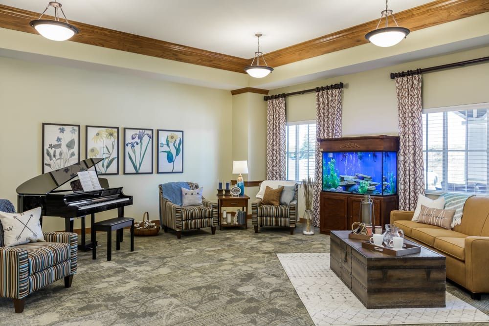 A cozy living room featuring a piano, comfortable seating, and a vibrant aquarium.