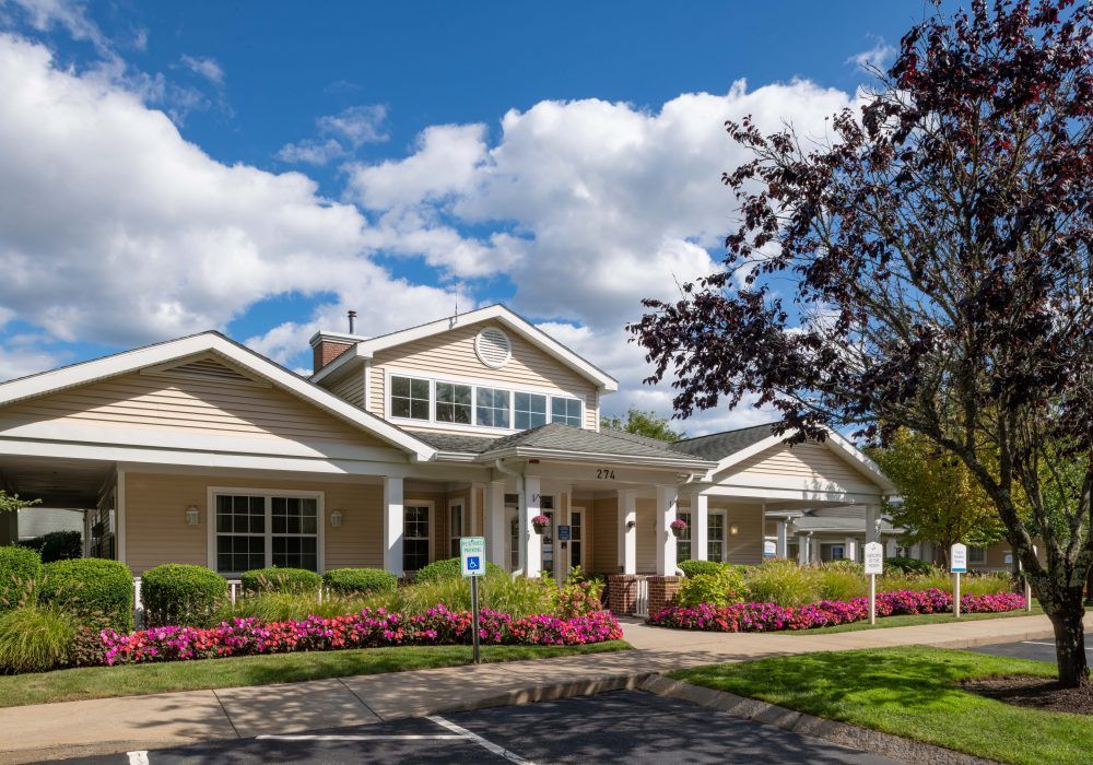 A suburban building surrounded by a well-maintained garden under a partly cloudy sky.