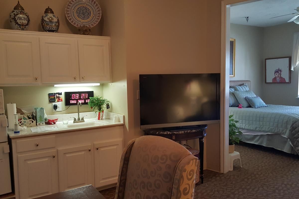A cozy living room with a TV and a kitchenette.