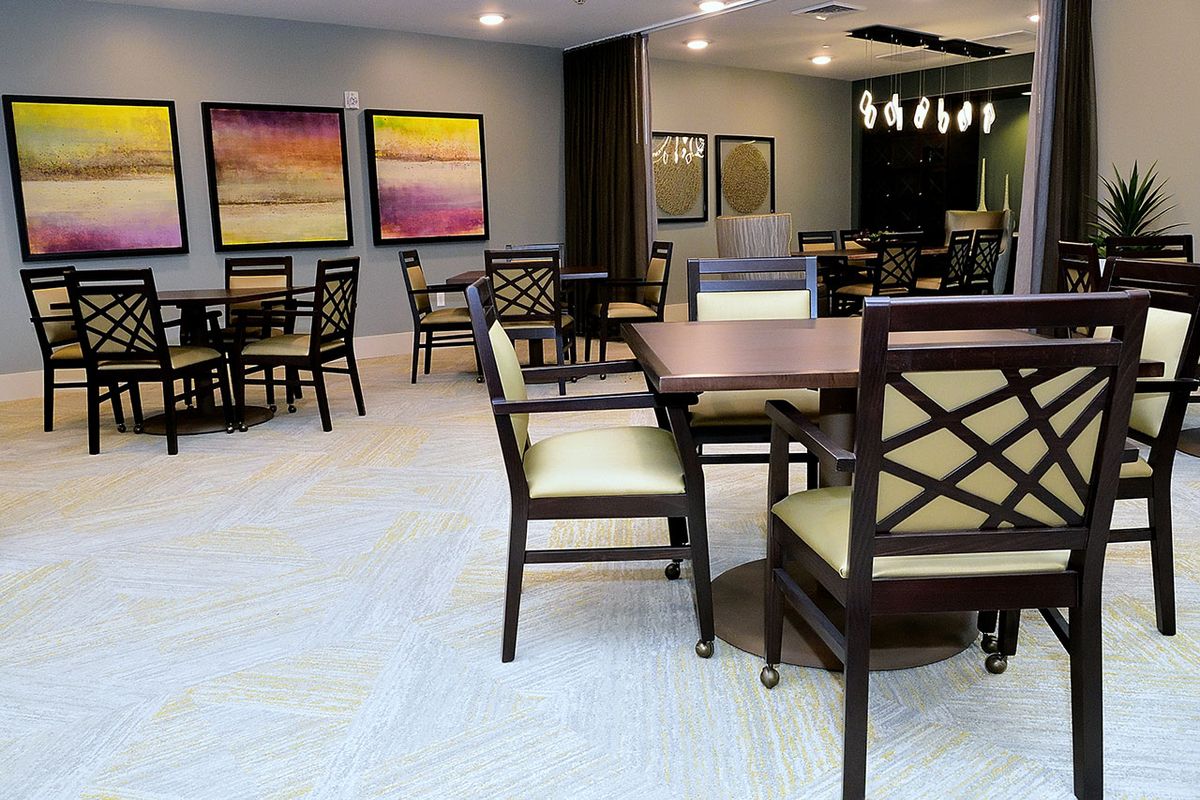 A modern dining area with tables, chairs, and colorful artwork on the walls.
