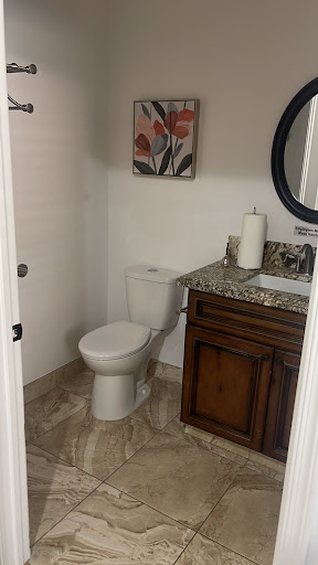 A well-appointed bathroom featuring a modern toilet, elegant vanity with granite countertop, and decorative artwork.