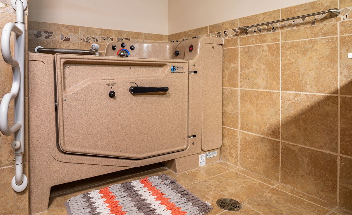 A bathroom with a specialized bathtub designed for accessibility, featuring tiled walls and floor with a colorful rug.