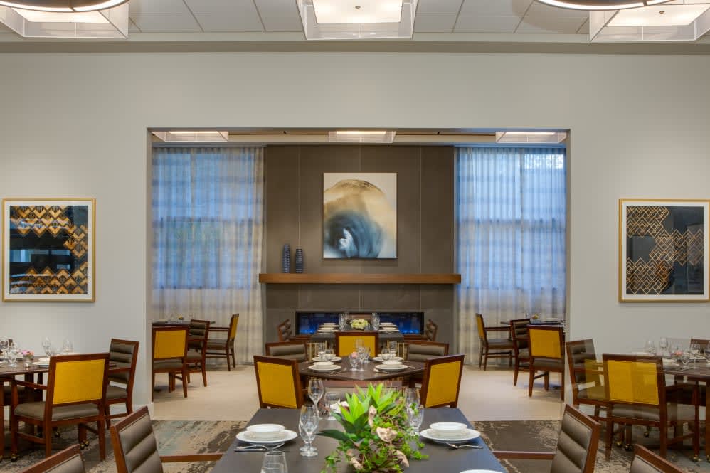 A modern dining room with elegant decor, featuring a central fireplace and contemporary artwork.
