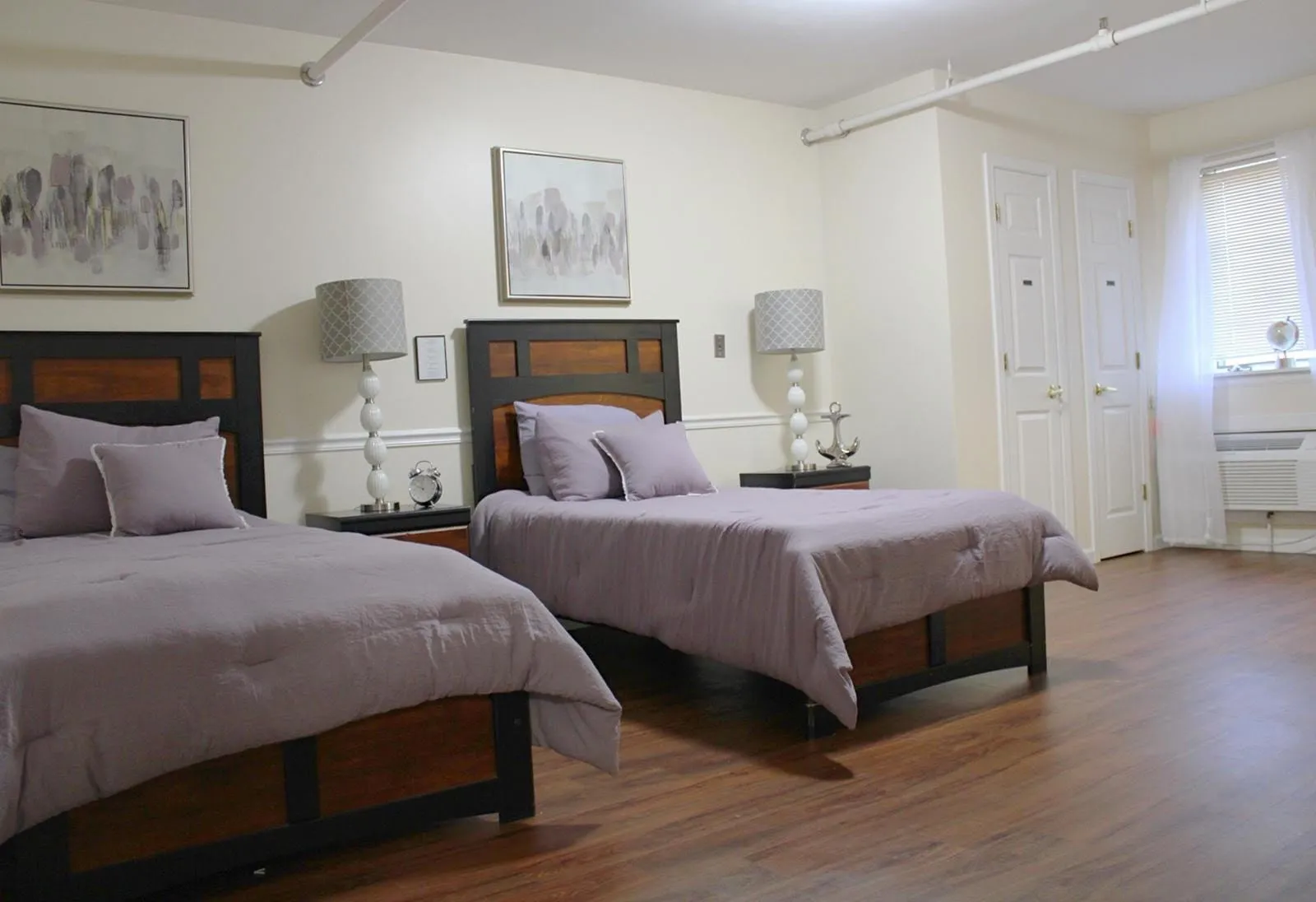 A cozy bedroom with two twin beds, elegant lamps, and wooden flooring.