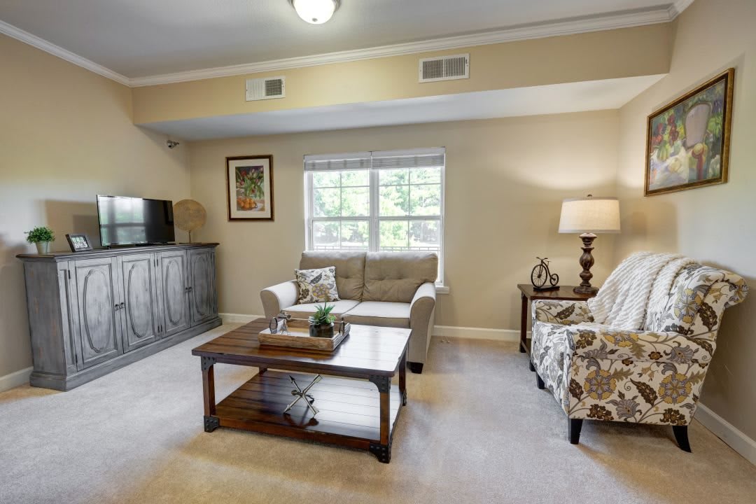 A cozy living room with a sofa, coffee table, and TV, decorated in neutral tones.