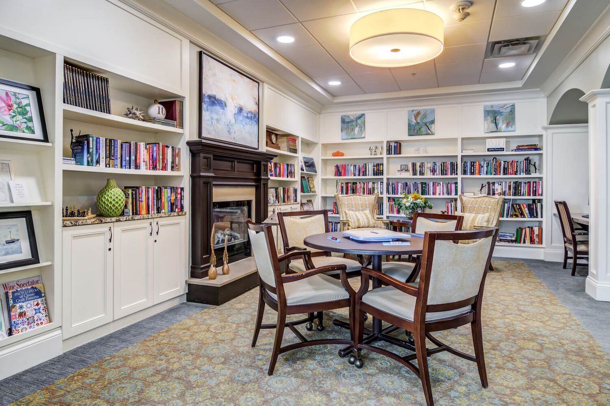A cozy library with bookshelves, a fireplace, and a seating area for reading.