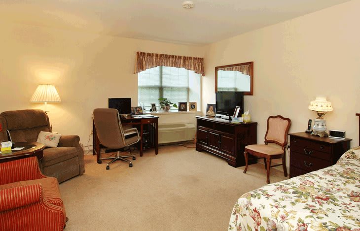 A cozy bedroom with a desk, computer, and comfortable seating.