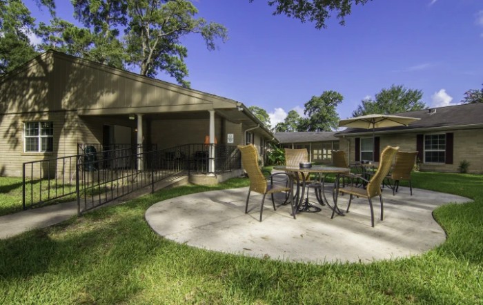 A sunny outdoor patio area with a table and chairs.