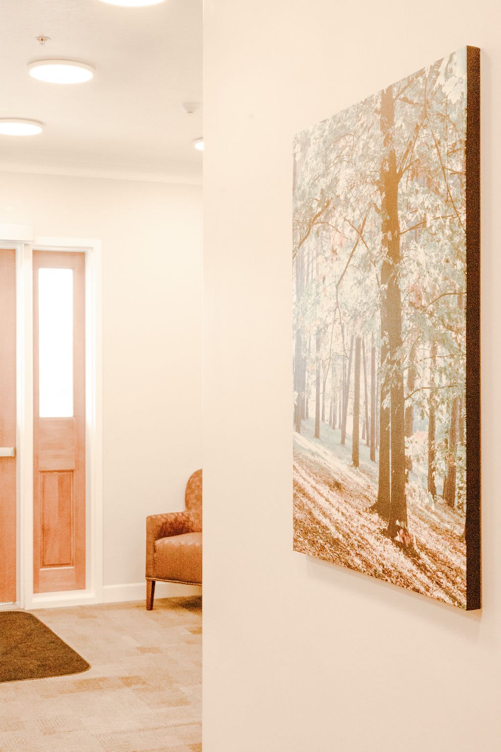 A cozy hallway featuring a forest-themed painting and a wooden door.