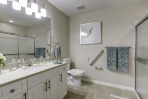 A modern bathroom with a large mirror, white vanity, and decorative elements.