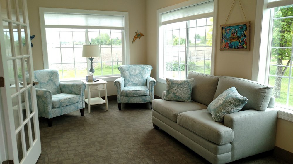 A cozy living room with a sofa, armchairs, and large windows allowing natural light to fill the space.