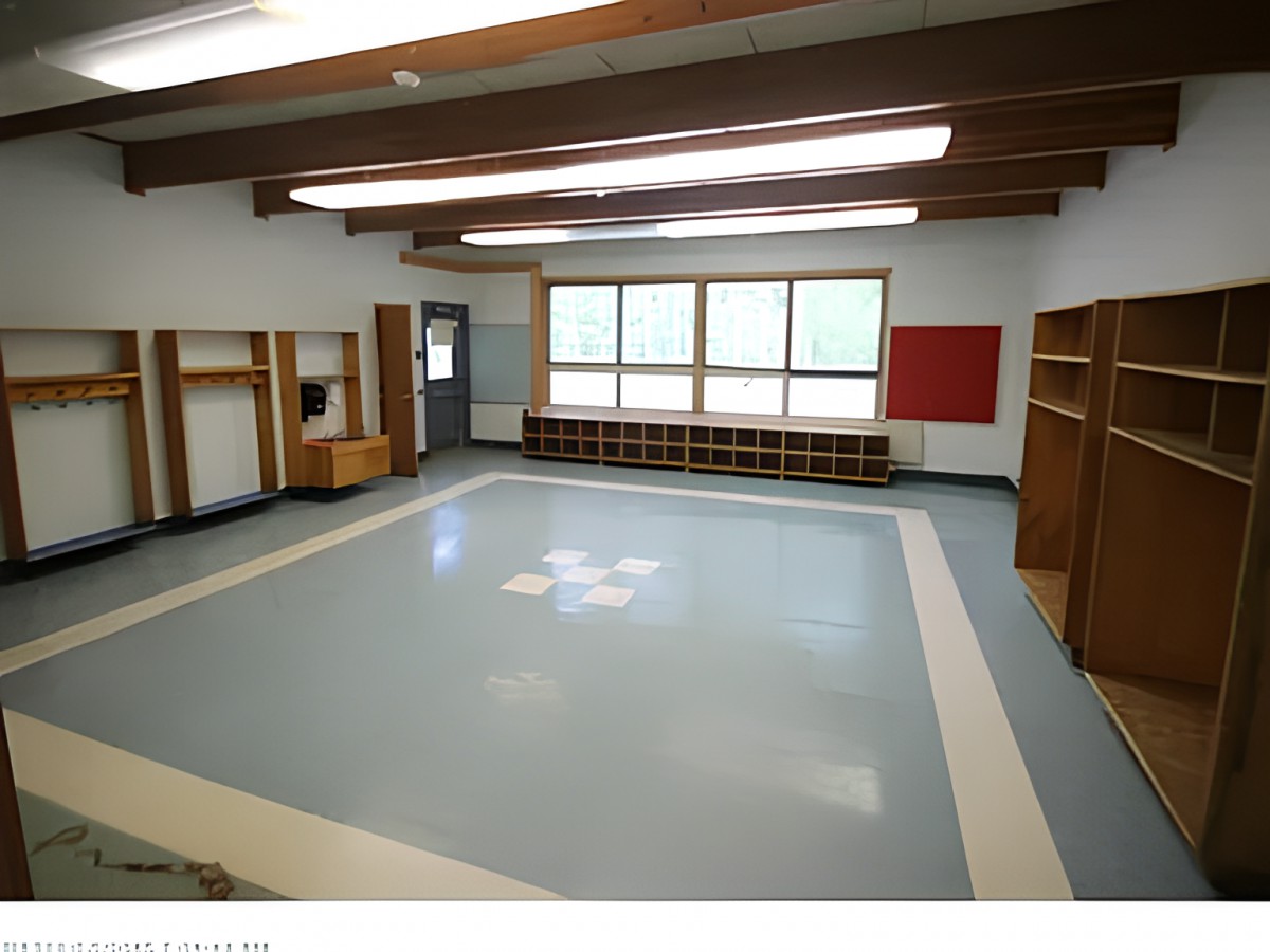 An empty classroom with wooden beams and cubbies, featuring large windows.