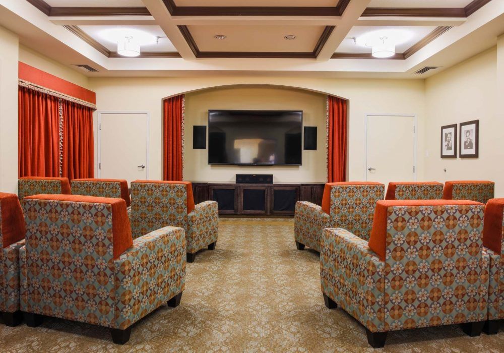 A cozy home theater room with patterned seating and a large television screen.