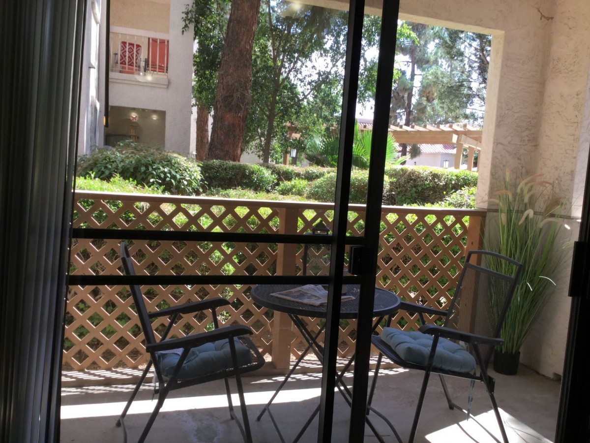 A cozy patio area with a table and chairs overlooking a garden.