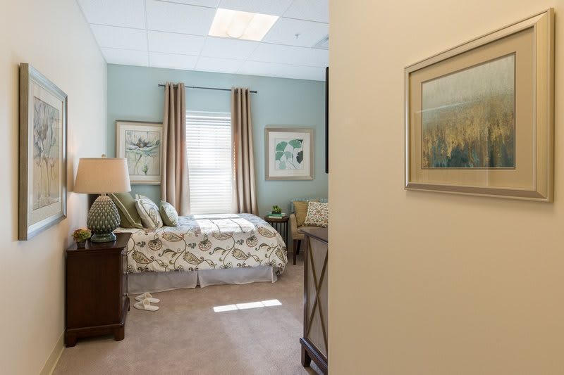 A well-decorated bedroom featuring a comfortable bed, elegant curtains, and wall art.