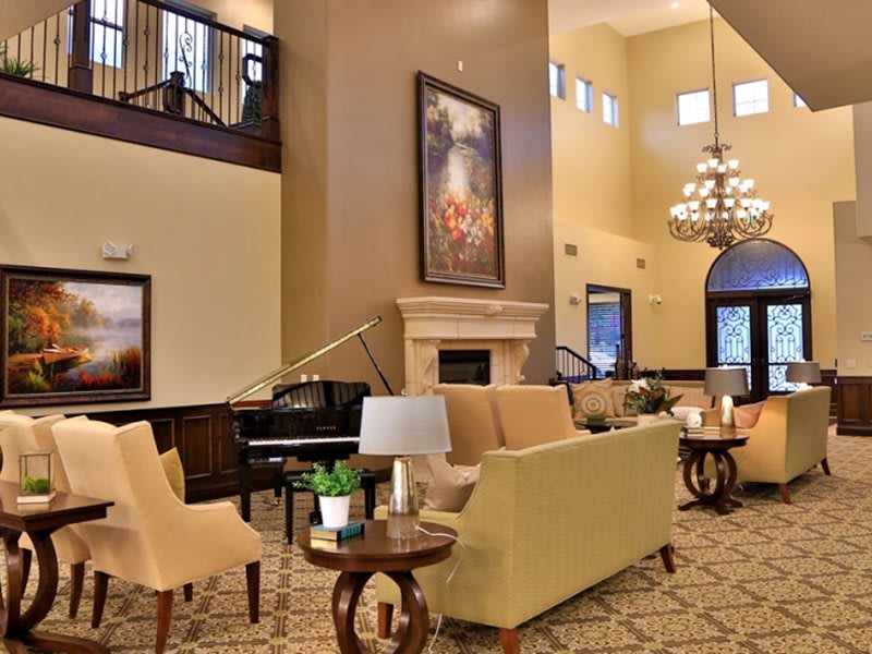 A luxurious hotel lobby featuring elegant sofas, a grand piano, and a large chandelier.