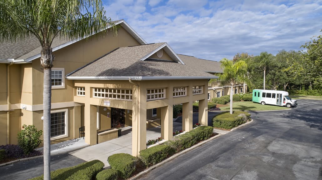A hotel entrance surrounded by well-maintained landscaping and palm trees.