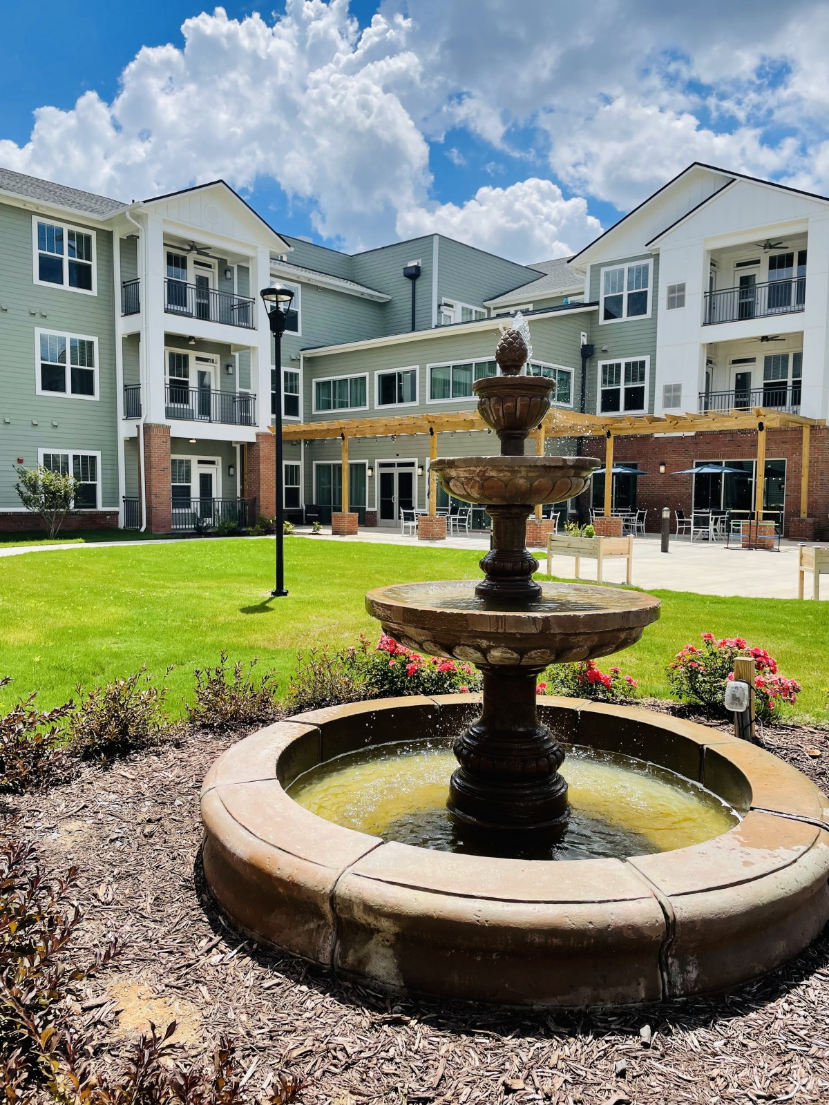 A scenic view of a residential building with a central fountain and landscaped garden.