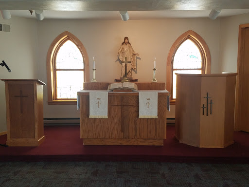 A serene view of an altar inside a church with wooden decor and arched windows.