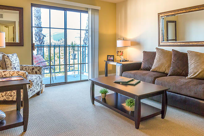 A cozy living room with a sofa, coffee table, and large window overlooking the outdoors.