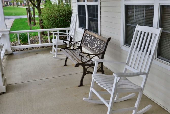 A cozy porch with rocking chairs and a decorative bench, perfect for relaxation.
