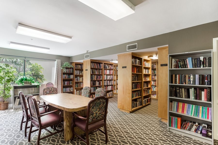 A cozy library space with bookshelves, a table, and chairs for reading.