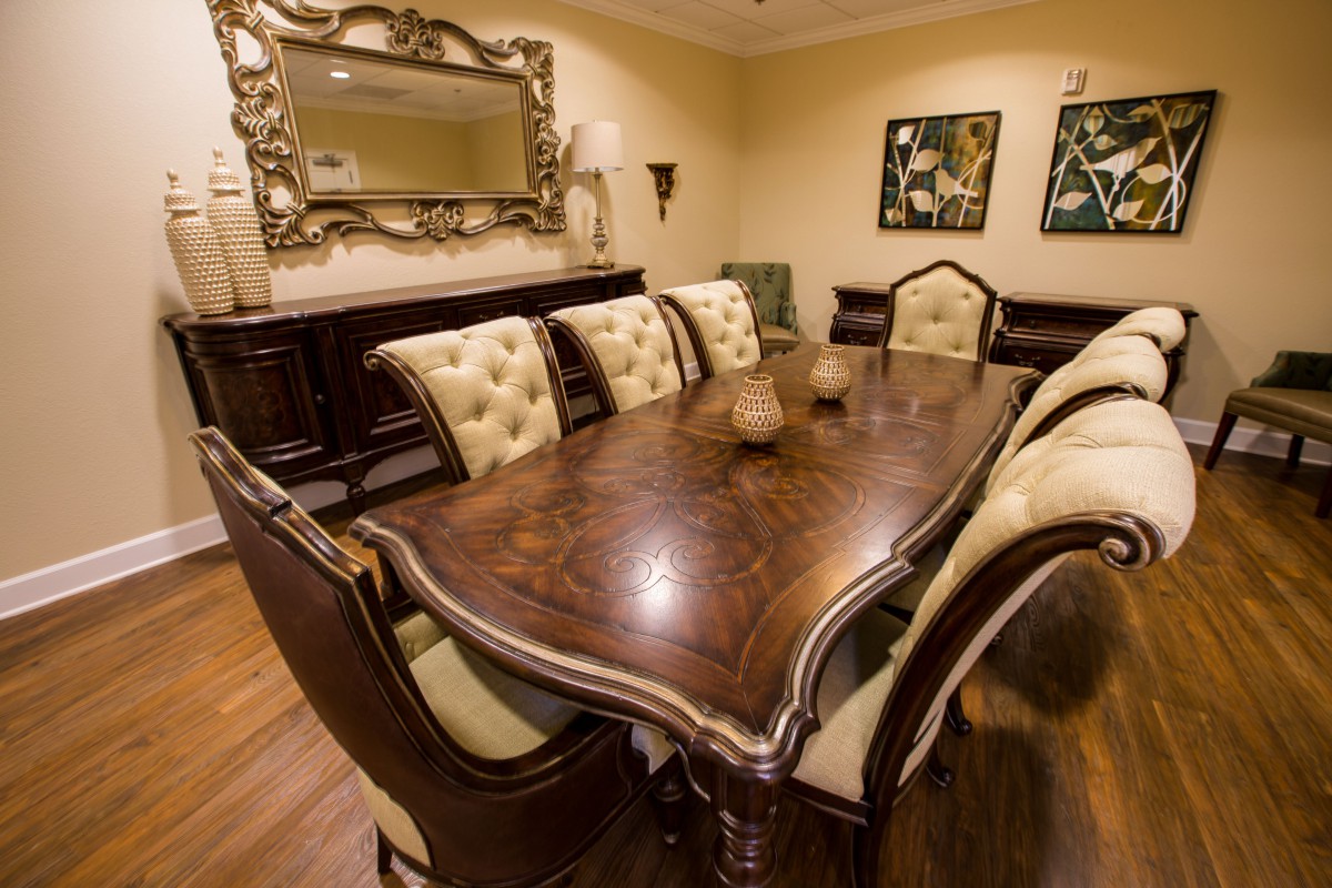 An elegant dining room featuring a large wooden table with upholstered chairs and decorative elements.