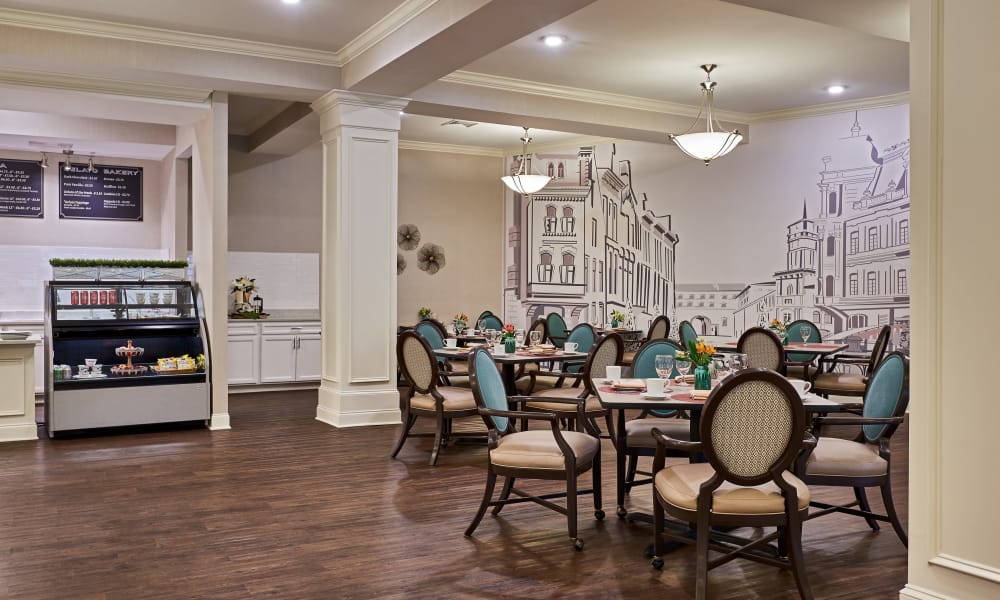 An elegant dining room with neatly arranged tables and chairs, adorned with decorative wall art and illuminated by stylish chandeliers.