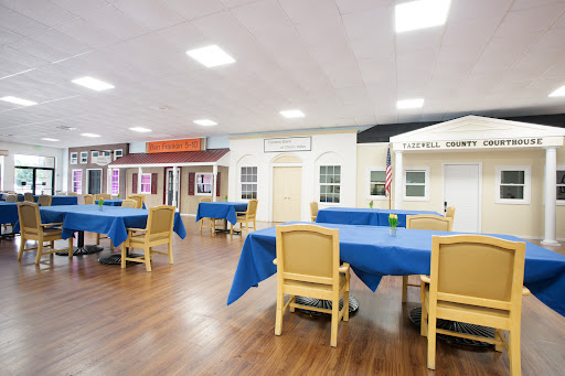 A spacious dining area featuring tables with blue tablecloths and decorative building facades.