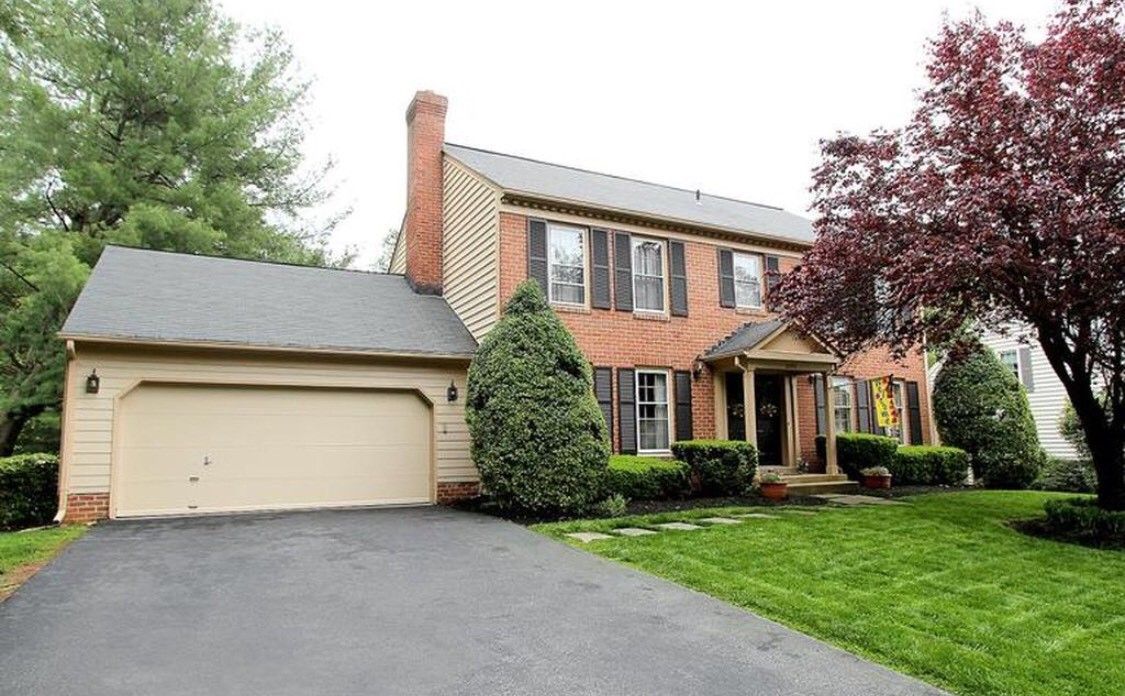 A two-story brick house with a garage and well-maintained lawn.