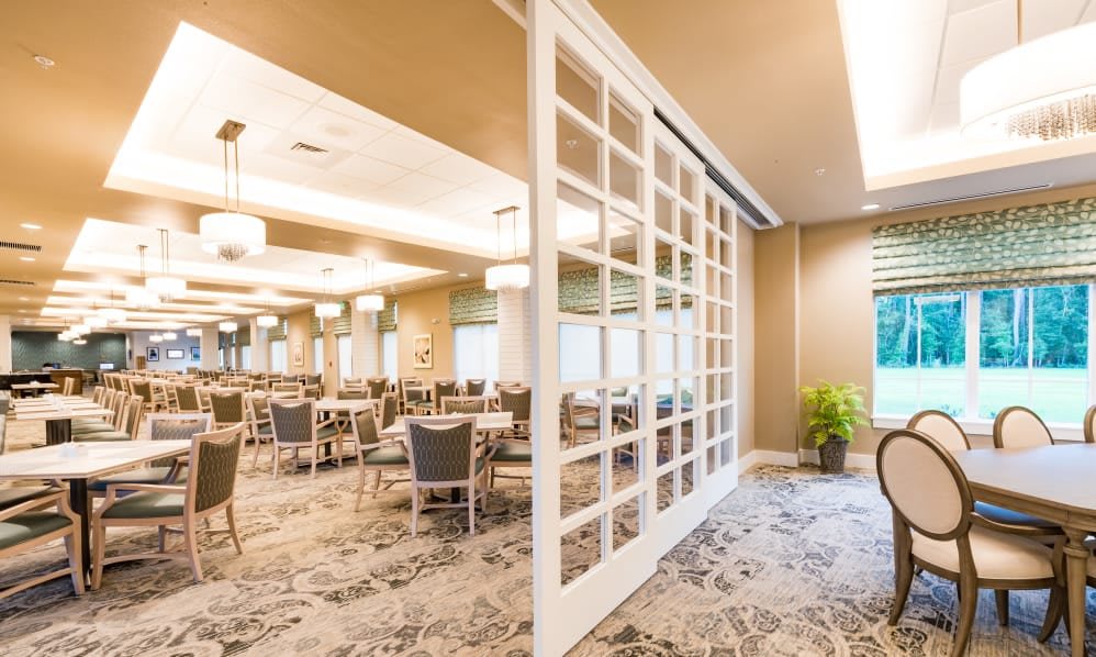 A spacious and modern dining area featuring elegant tables and chairs, with stylish lighting and a carpeted floor.
