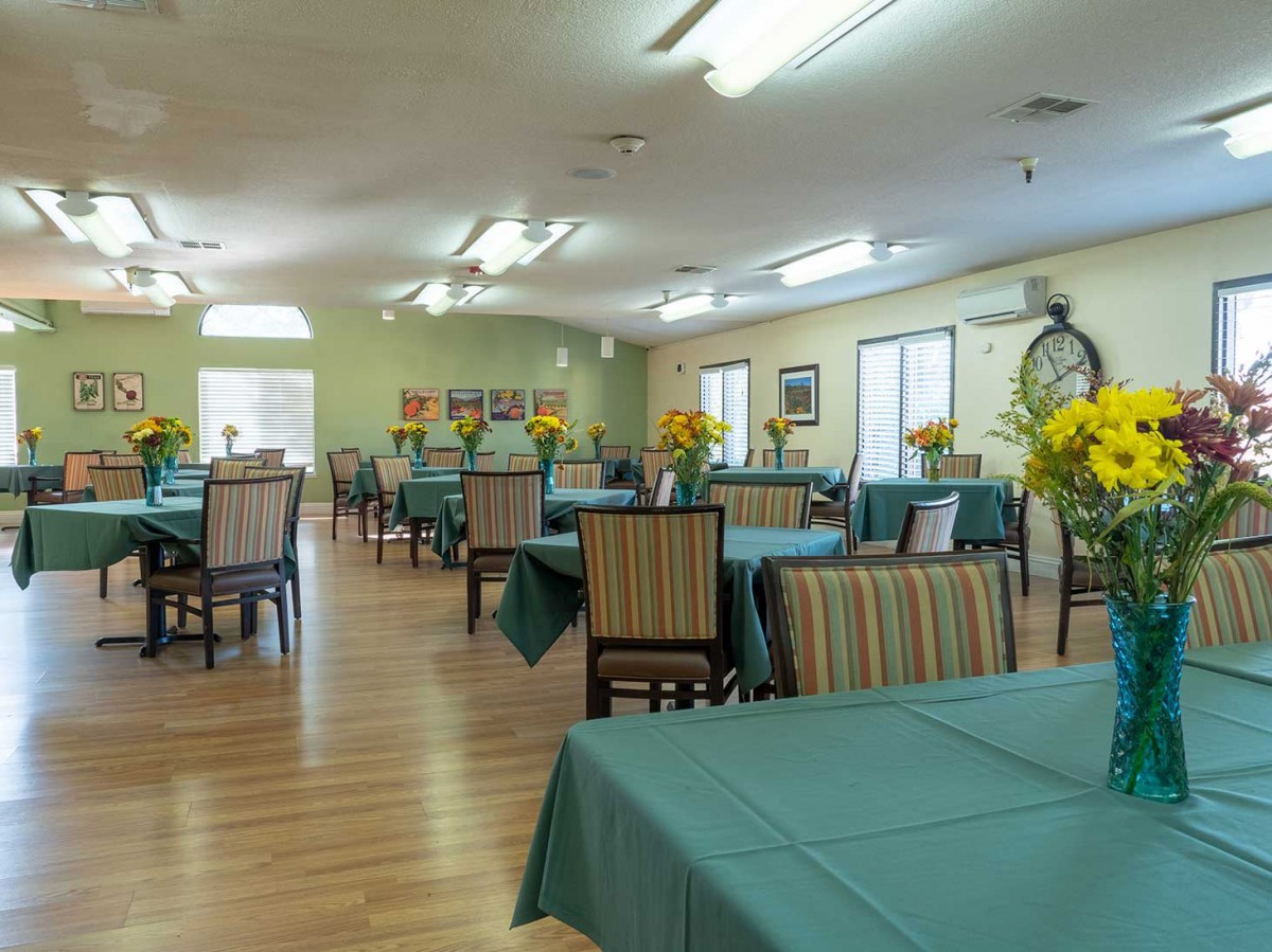 A spacious dining room with neatly arranged tables and chairs, decorated with fresh flowers.