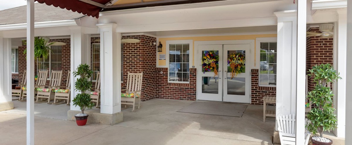 A building entrance with a rocking chair and decorated double doors.