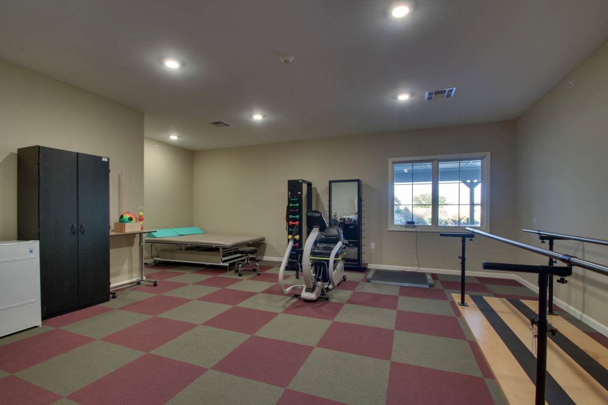 A well-equipped exercise room with therapy tables and fitness equipment.