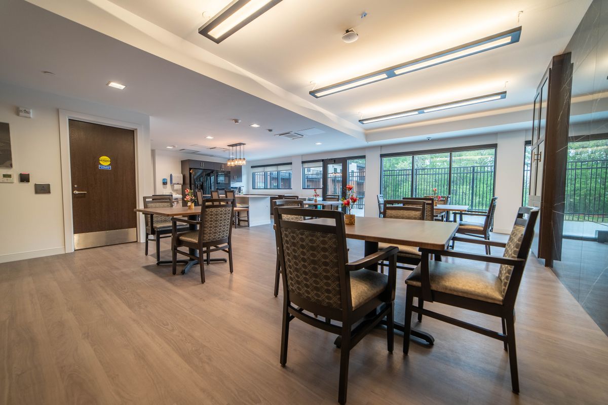 A modern dining area with tables and chairs, well-lit with large windows.