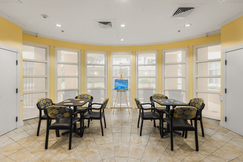 A bright meeting room with tables and chairs surrounded by large windows.