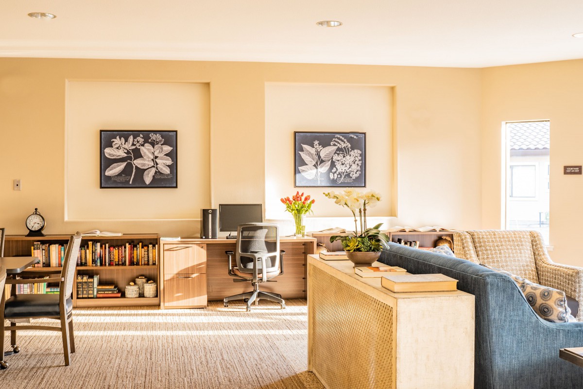 A well-lit home office space featuring a sleek desk, comfortable chair, and vibrant floral artwork.