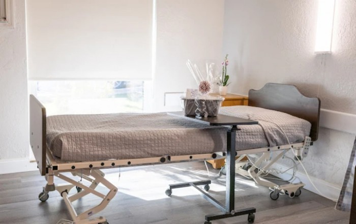 A hospital room featuring a medical bed, side table, and bright natural lighting.