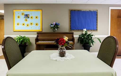 A cozy room featuring a piano, decorative flowers, and a simple table setting.