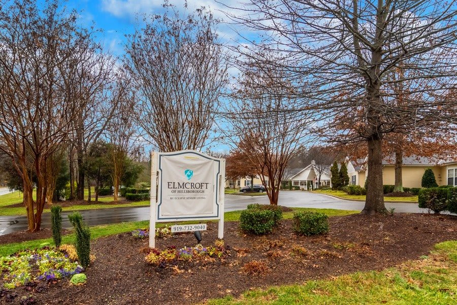 Entrance sign to a residential community with landscaped surroundings and overcast weather.