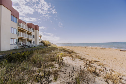 A serene view of a beachside residence with golden sand and a clear blue sky.